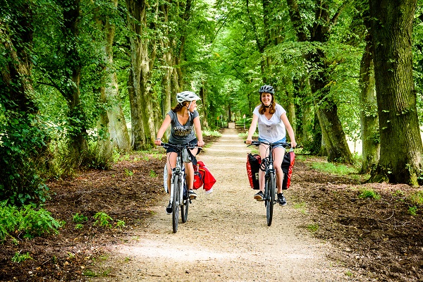 Twee meiden op fietsvakantie rijden over een bospad