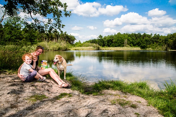 Mutter mit Kind und Hund genießen ihre Pause an einem See im Meinweg