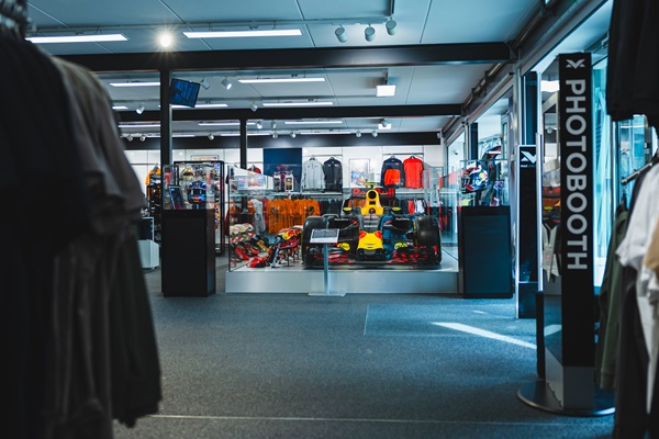 Das Innere des Max Verstappen Store in Swalmen, Teil der Radroute Im Windschatten. Der Laden zeigt ein Formel-1-Auto, umgeben von offiziellen Artikeln wie Kleidung und Accessoires.