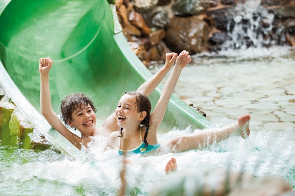 Junge und Mädchen rutschen eine Wasserrutsche im Ferienpark de Lommerbergen hinunter