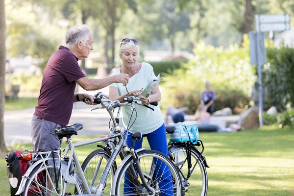 Ein älteres Ehepaar steht bei einer Radtour in der Gemeinde Leudal neben ihren Fahrrädern und schaut auf eine Karte.