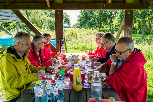 Groep is aan het eten in de natuur onder een afdak in De Groote Peel