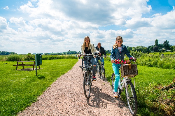 Vader fietst met 2 dochters langs de Maas in de gemeente Beesel