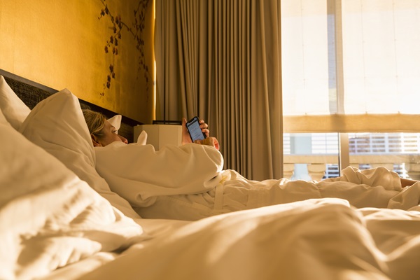 Vrouw kijkt op haar telefoon net nadat ze wakker is geworden op haar hotel in Weert
