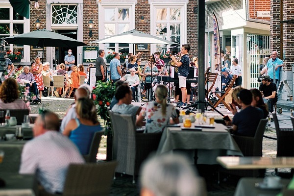 Bands spielen Musik vor einer vollen Terrasse auf dem Marktplatz in Maaseik in Belgien