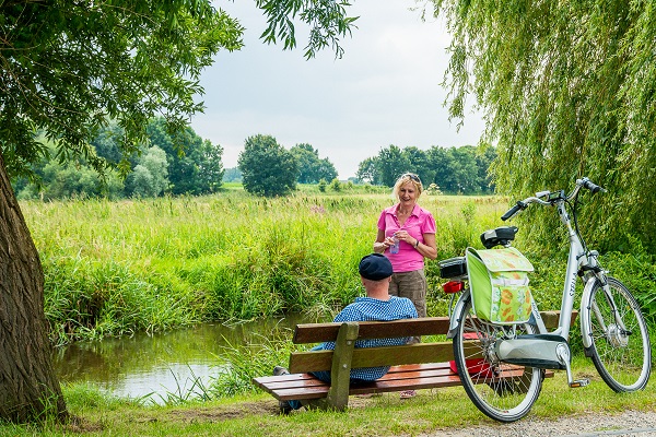 Uitrusten tijdens de tocht langs fietsknooppunten op een bankje in Asselt