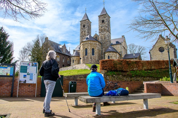 Langs het Pieterpad ligt de Basiliek van St. Odiliënberg waar deze wandelaars rusten op een bankje