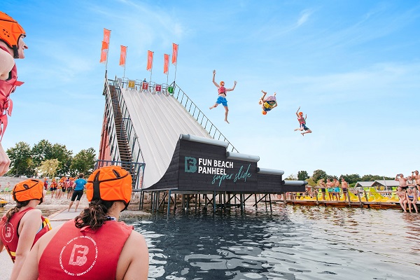 Mensen glijden van de superslide bij Funbeach Panheel terwijl anderen toekijken