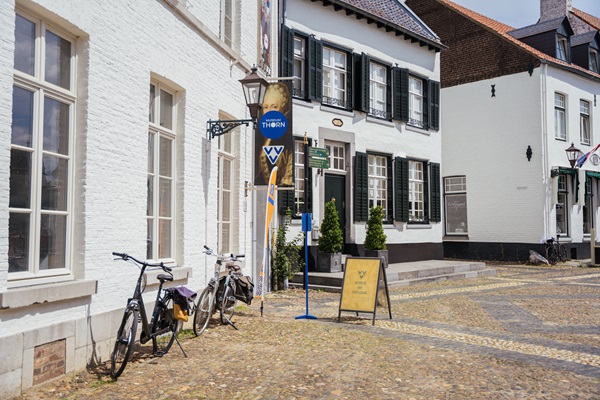 VVV Thorn with bikes in front of the facade and the pavement sign and beach flag outside in front of the door