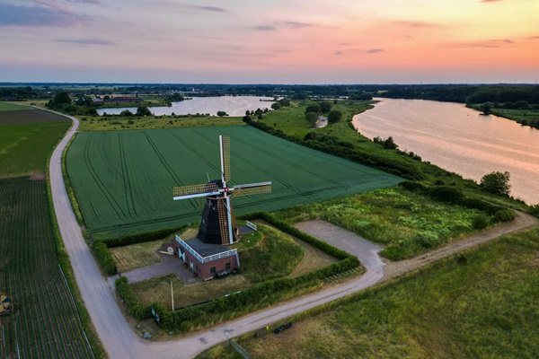 Aerial photo of the Grauwe Beer windmill in Beesel, surrounded by fields with views of the Meuse at sunset.