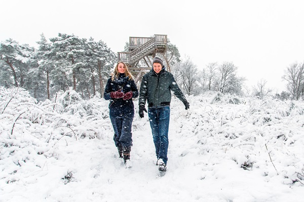 Two hikers in the snow near a lookout tower in the Meinweg during a winter walk.