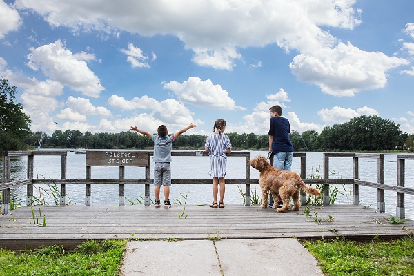 Kinderen staan met hun aangelijnde hond aan het water