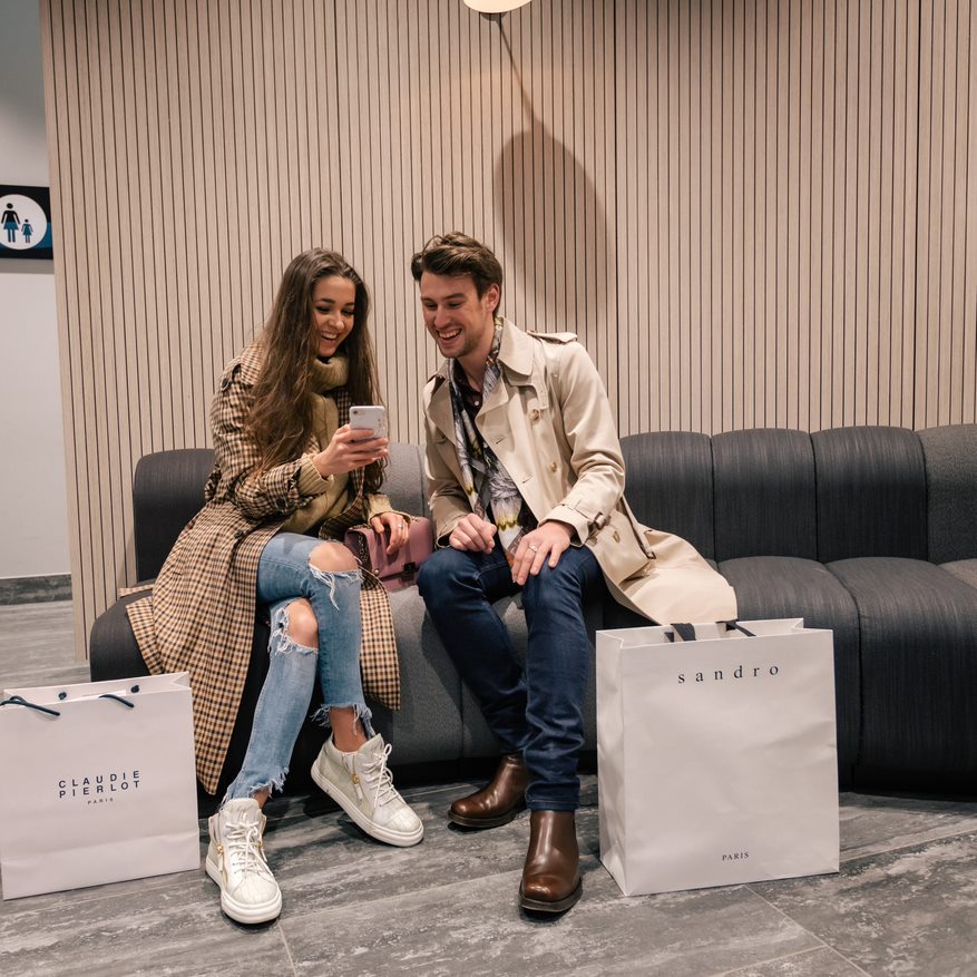 Man en vrouw kijken op de telefoon in één van de winkels van het Designer Outlet Roermond