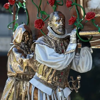 Kunstwerk van Studio Job in Weert, met goudkleurige, gedetailleerde figuren in renaissancekleding die een versierd object met rode rozen dragen.