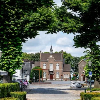 Dorpsplein in Stevensweert met zicht op het Maaseiland Museum, omringd door bomen en historische gevels.