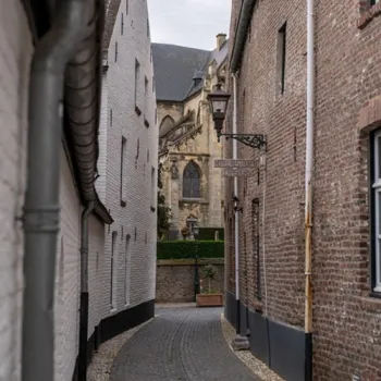 Smalle historische straat in Thorn met witte en bakstenen gevels en zicht op een kerk aan het einde van de straat.